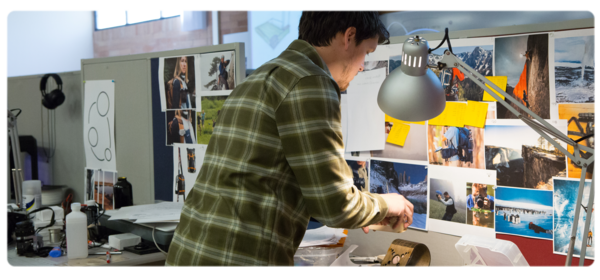 A product design student works at a lab workstation covered in colorful inspiration photos